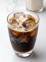 Iced Coffee Delight: A captivating shot of a refreshing iced coffee drink, ice cubes cooling the dark brew as cream swirls in, promising a delightful sensory experience.