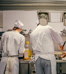 Group of professional chefs preparing food in a busy restaurant kitchen. Teamwork, precision, and culinary expertise in a high-pressure cooking environment.