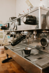 Espresso machine brewing fresh coffee into a metal cup at cafe