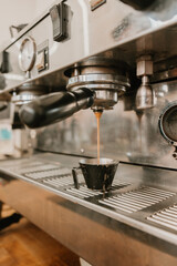 Espresso machine brewing fresh coffee into a metal cup at cafe