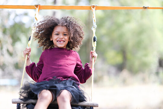 Smiling child swinging outdoors, enjoying a playful sunny day