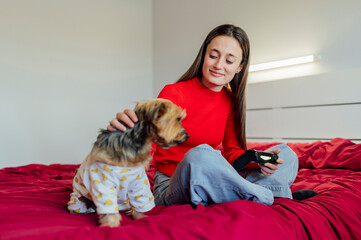 Young woman playing video games and petting her Yorkshire Terrier dog