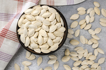 A bowl of pumpkin seeds on a gray background