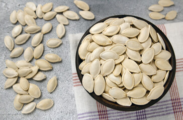 A bowl of pumpkin seeds on a gray background
