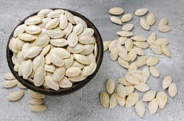 A bowl of pumpkin seeds on a gray background