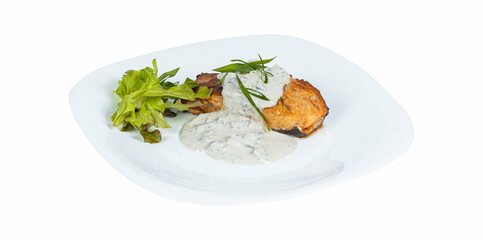 Grilled salmon steak with white sauce and herbs on a plate on a white background