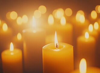 Close-up of burning candles illuminating the dark, surrounded by a warm glow of numerous lit candles.