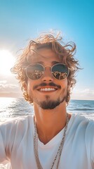 Smiling young man with curly hair and sunglasses enjoying a beach day.