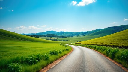 Fototapeta premium Serene Rural Road, Lush Fields, Blue Sky, Hilly Landscape