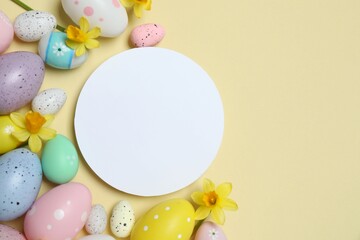 Happy Easter. Colorful eggs and yellow flowers on a pastel color background, space for text or advertising