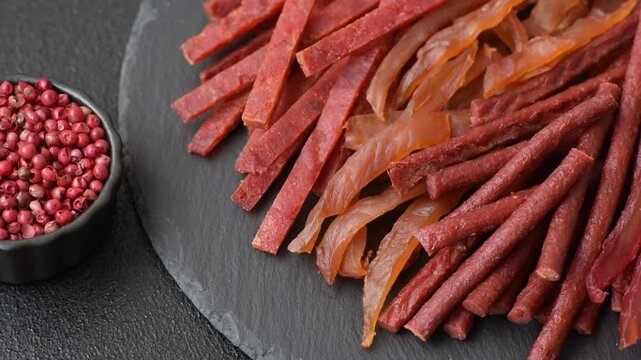 Jerky, dried fish in the form of sticks with salt, spices and herbs on a dark concrete background