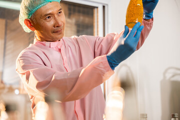 In a beverage factory a man in uniform meticulously inspects Basil seed products for quality. His...