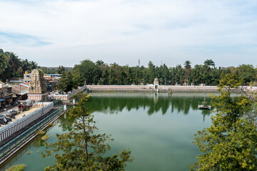 Fototapeta premium The tranquil surroundings of Shravanabelagola, with its sacred tank surrounded by ancient temples and lush greenery under a clear sky.