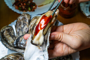 steamed oyster with gochujang sauce on the hand