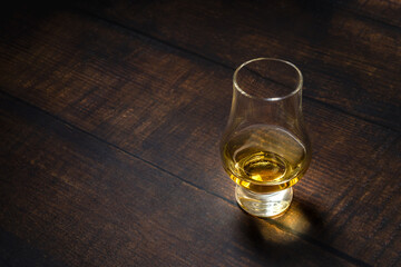 Close-up of single malt whiskey or scotch whisky tasting glass on dark wooden table