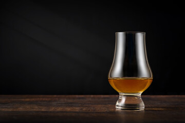 Close-up of single malt whiskey or scotch whisky tasting glass on dark wooden table