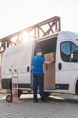 Delivery driver loading boxes into van for shipment. Delivery driver concept in a van. Man in blue...