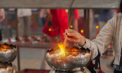 Woman holding smoking incense sticks in chinese temple during Chinese New Year.