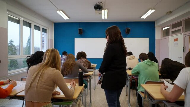 Teacher walking through classroom during exam, supervising students