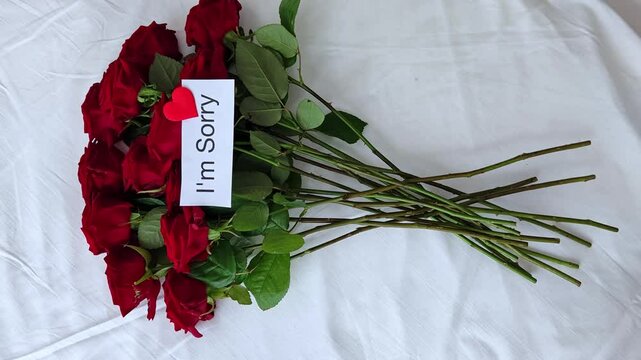 Bright bouquet of red roses with white card with the inscription text i am sorry, the concept of apologies. 