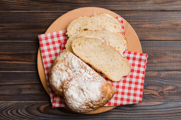Freshly baked bread slices on cutting board against white wooden background. top view Sliced bread