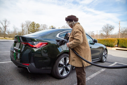 A well dressed older woman plugs in her electric vehicle