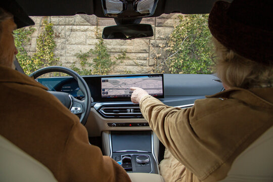 An elderly woman pointing at a digital map sitting in a car