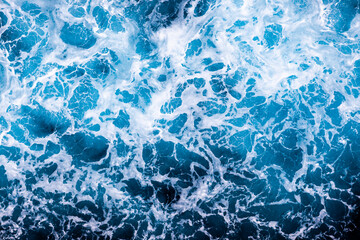 Ocean water surface texture. Aerial view of artistic water with foam. Can be used in covers, packaging, posters, textures, presentations, art, and design projects. Amazing nature background image.