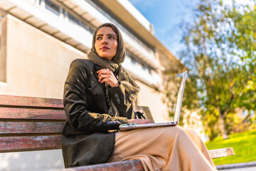 Muslim businesswoman working with laptop outdoors in a park