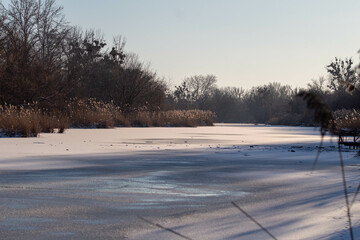 Obraz premium Serene Winter Scene with a Partially Frozen River Flowing Through the Forest