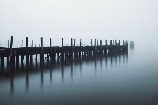 Fototapeta Serene, foggy pier extending into calm waters, creating a tranquil and mysterious atmosphere.