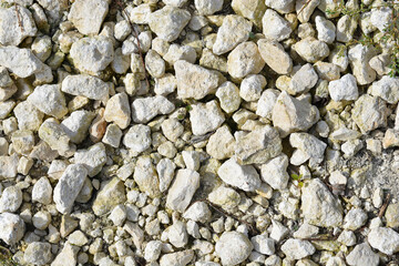 A close-up of a pile of rough, light-colored stones, showcasing their varied textures and irregular shapes
