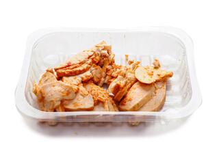 A tray of Cajun style chicken is on a white background. The chicken is cut into pieces. Small...