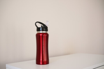 Fototapeta premium A Stylish Red Water Bottle Placed on a White Surface, Perfect for OntheGo Drinks or Workouts