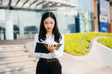 Successful businesswoman works outdoors near the office holds a tablet