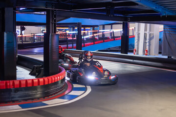 Child, driving go cart car in an indoor race track, enjoying sport