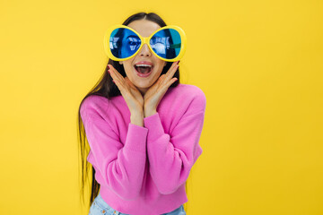 excited pretty girl dressed in pink and sunglasses look with shock at discounts isolated on yellow color background