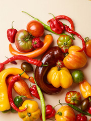 pile of tomatoes and different peppers over beige background