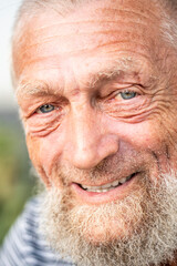 Portrait of an elderly man in retirement, enjoying peaceful moments outdoors, smiling contently, showing physical and mental wellbeing, wearing casual clothes, close-up with wrinkles, gray hair