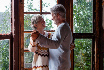 Elderly couple dancing indoors at mountain chalet during vacation in modern home setting showcasing...