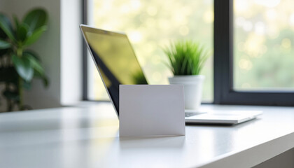 A mockup featuring an open laptop with a blank screen and a business card on a modern desk, ideal for business branding presentations.
