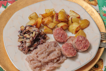 dettagli di un tradizionale piatto casalingo natalizio del Friuli Venezia Giulia, nell'Italia nord-orientale, a base di patate al forno, crauti, radicchio cotto e cotechino