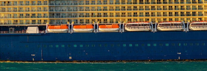 Safety equipment lifeboat. Orange lifeboat hanging over Sea on the side of a Cruise ship.