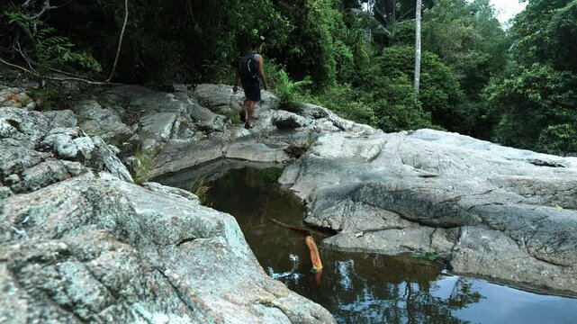 A tourist walks along the rocks towards the descent along the bed of a mountain river