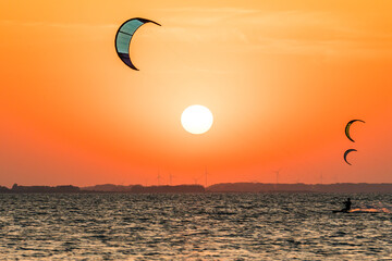 Kitesurfing at the baltic sea in beautiful orange sunset