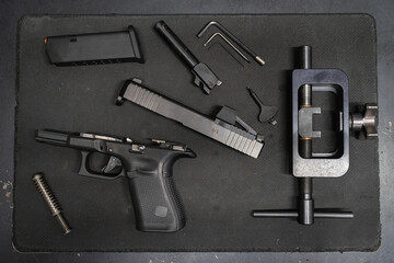 Installation and replacement of sights on a modern 9mm pistol in a workshop by a gunsmith.
