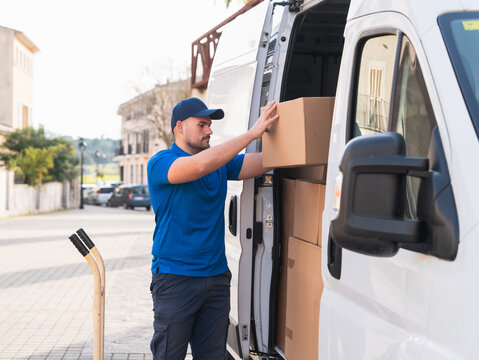 Delivery driver organizing packages in a delivery van. Delivery driver concept in a van. Man in blue uniform arranging boxes inside a delivery vehicle, representing logistics and shipping.