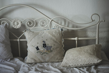 Romantic cushions with vintage white crocheted covers, white cast iron bedpost