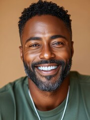 Obraz premium Smiling man with joyful expression poses against a warm background in a casual green shirt showcasing a confident and inviting demeanor during daylight