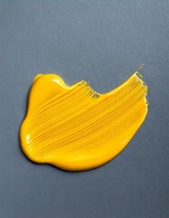 Mustard yellow stroke of acrylic paint on a grey background 